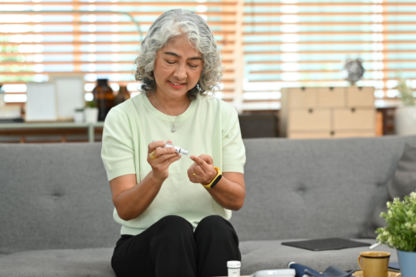 Person smiling while testing their blood sugar.