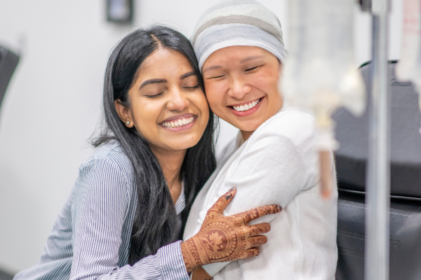 A younger person hugging older person wearing a headscarf in hospital