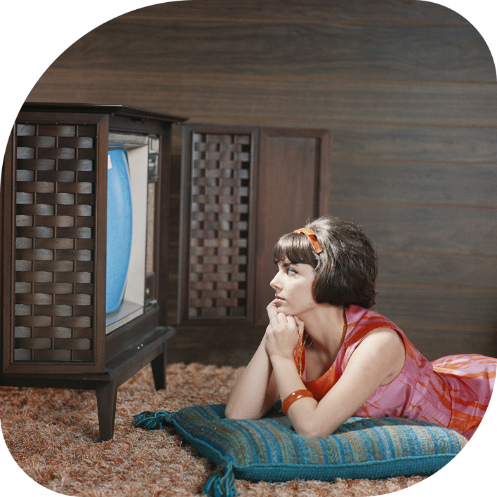 Woman in 1960s laying on the floor watching a television set