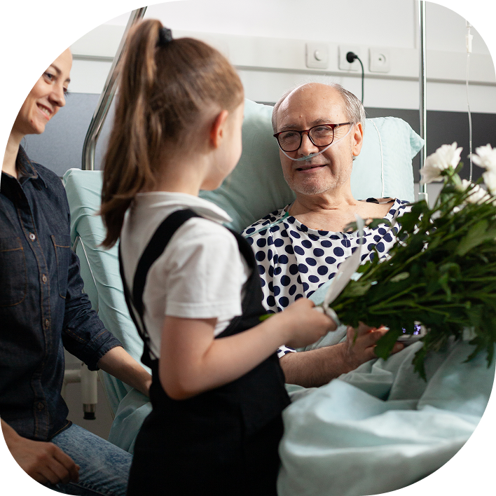 granddaughter bringing flowers to her grandfather in the hospital where he's recovering from transplant surgery