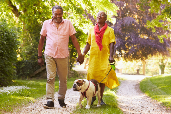 Happy couple walking their dog in the sun
