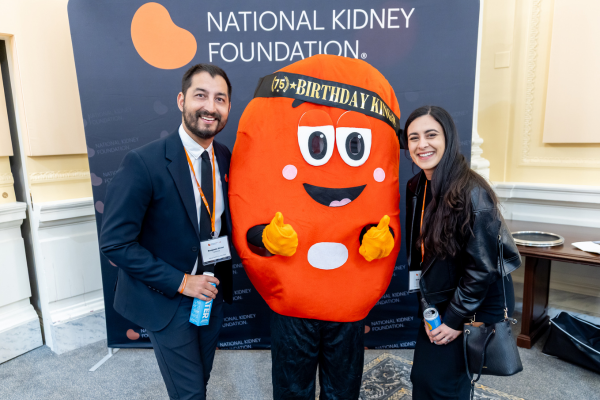 Two happy advocates on either side of kidney mascot