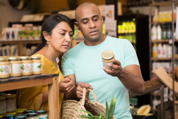 Two people looking at food label on jar.