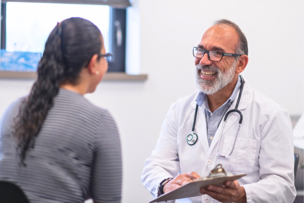 Doctor hablando felizmente con un paciente.