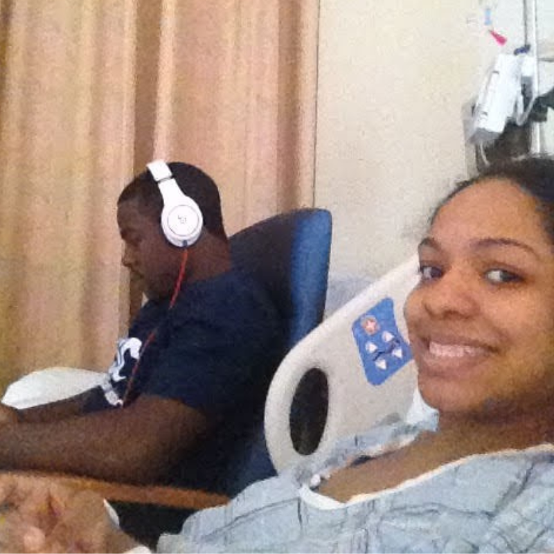 Nichole (R) smiling in a hospital bed with her brother in the background