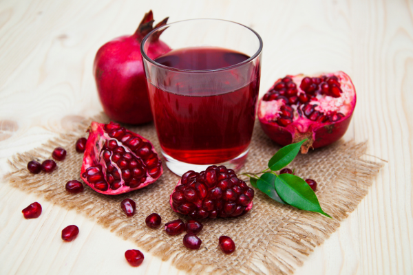 Open pomegranates next to glass of pomegranate juice
