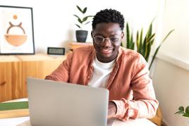 Man sitting at a table looking something up on his laptop