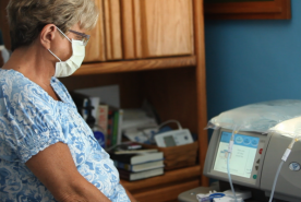 Older person looking at their PD machine in their home.