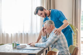 Empathetic nurse comforting upset patient looking a bills