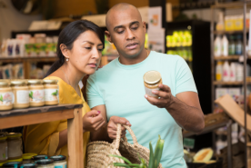 Two people looking at food label on jar.