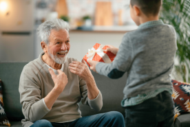 Older adult happily taking present from child.