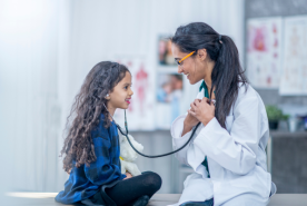 Child using stethoscope on doctor