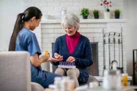 Older adult looking at medication with nurse