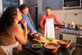 Two people laughing with person cooking
