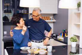 Person happily sharing food with another in a kitchen.