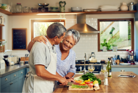 Two people smiling and cooking