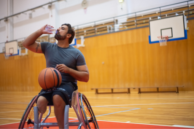 Person in wheelchair drinking water during basketball practice