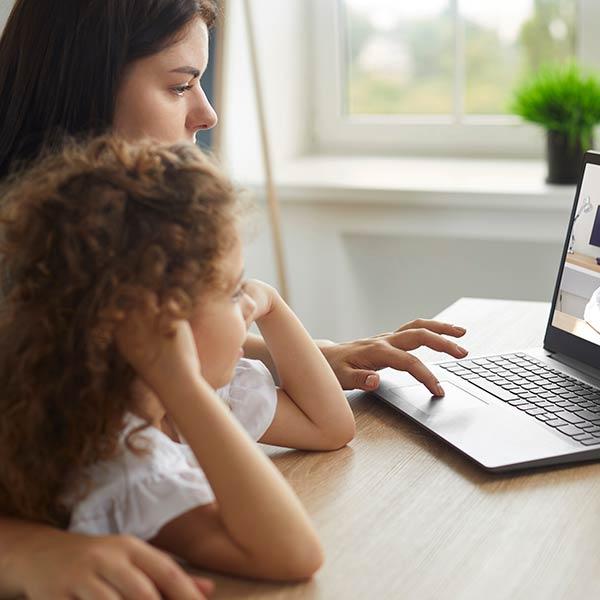 Mom and daughter looking at computer together at kitchen table