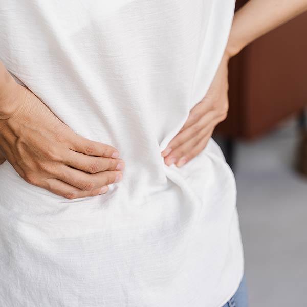 woman rubbing her lower back due to kidney pain