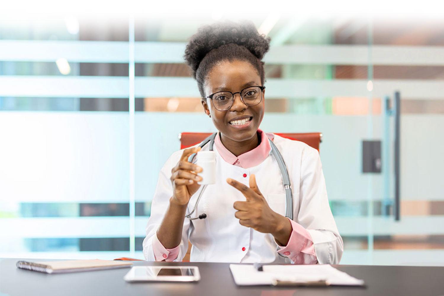 Doctor sitting at a desk holding up a urine cup