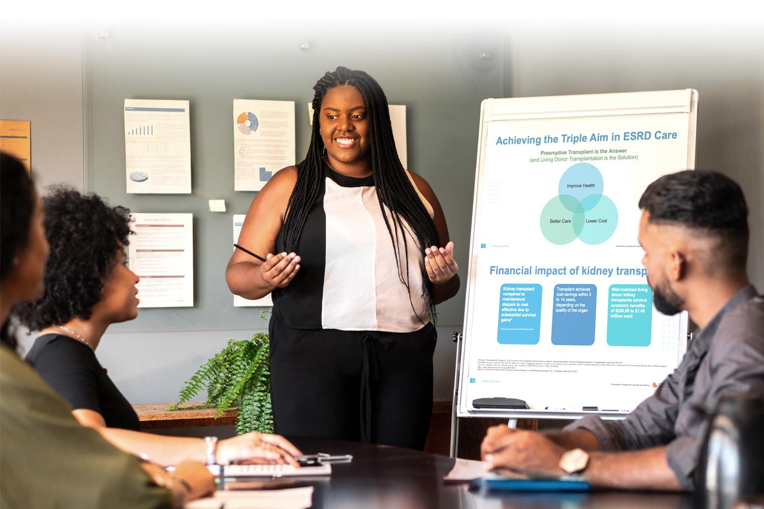 Woman presenting a Living Donation Business Case to a group of people in a conference room