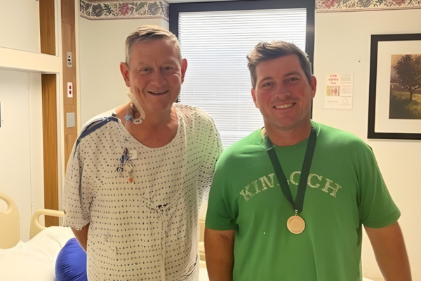 Bobby and Trevor standing by each other in hospital room