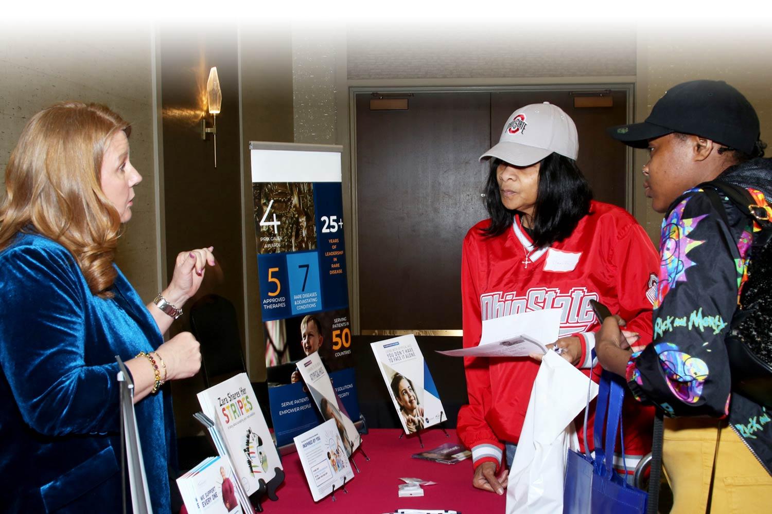 Two people at the Patient Symposium visiting a presentation table
