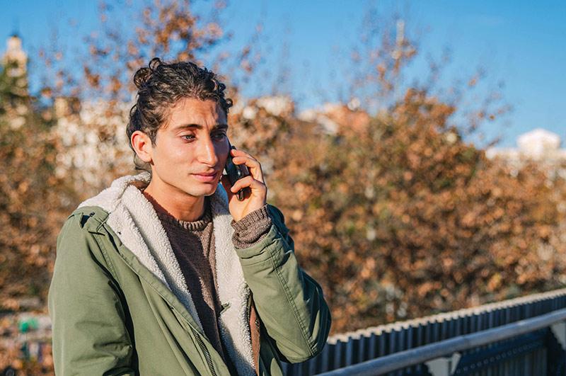 Man standing in a park talking on his cellphone