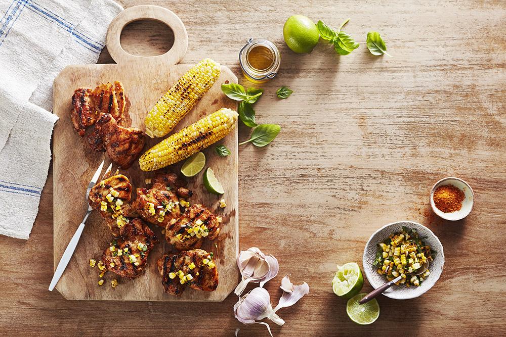 Pollo a la parrilla y maíz sobre una mesa de madera