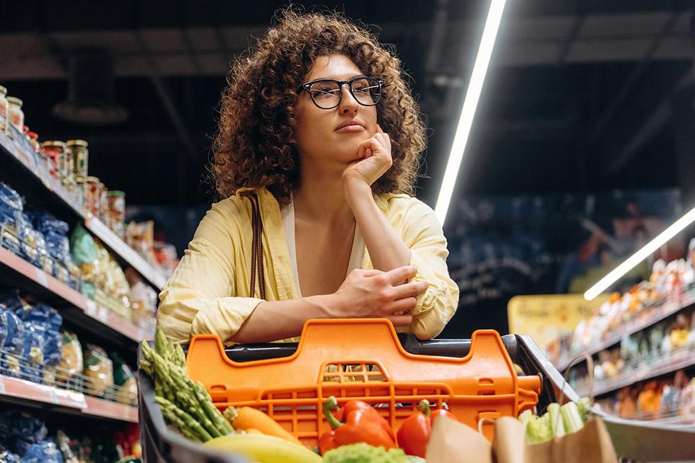 Una mujer pensativa con la compra en un supermercado