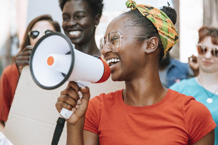 woman speaking into a megaphone in front of a group