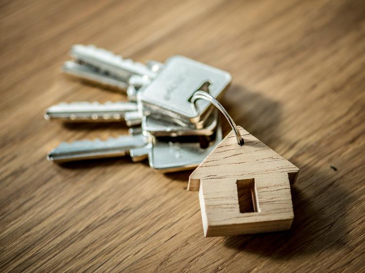 pair of keys with a house keychain laying on a table