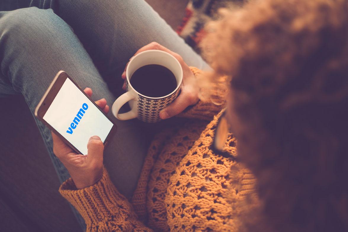 person looking at their smartphone with the "Venmo" logo displayed on the screen