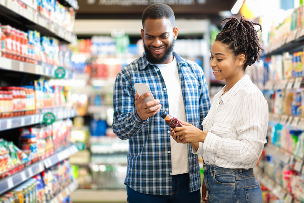 Two people reviewing the ingredients on a food nutrition label in a grocery store aisle