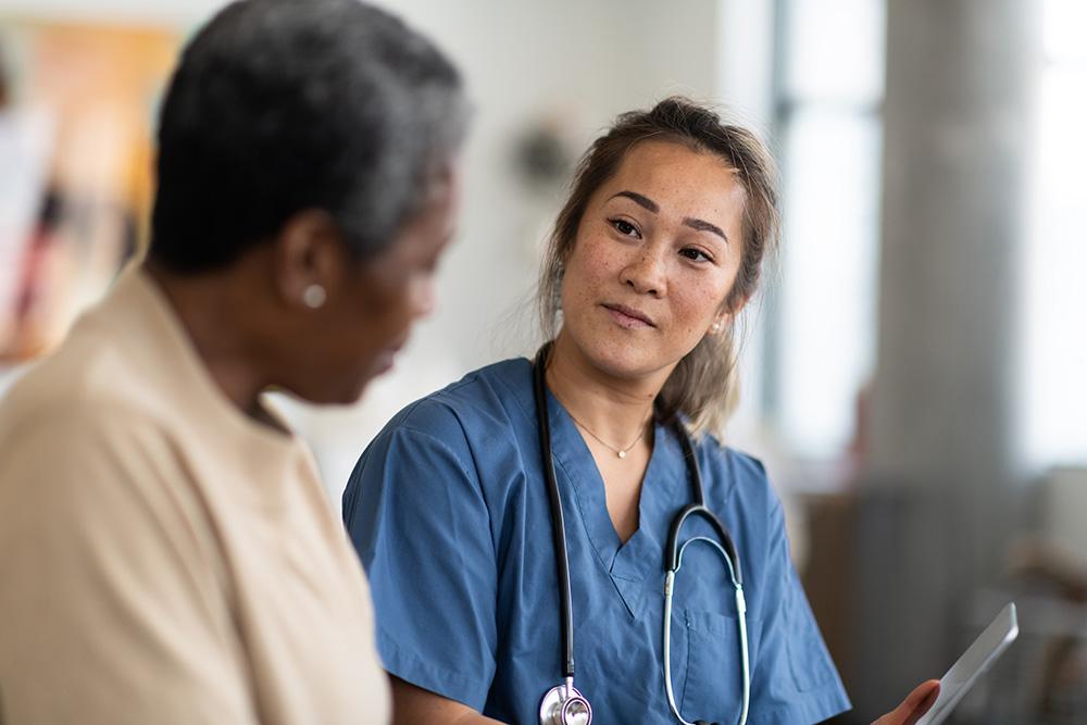 Asian doctor listening closely to a Black patient