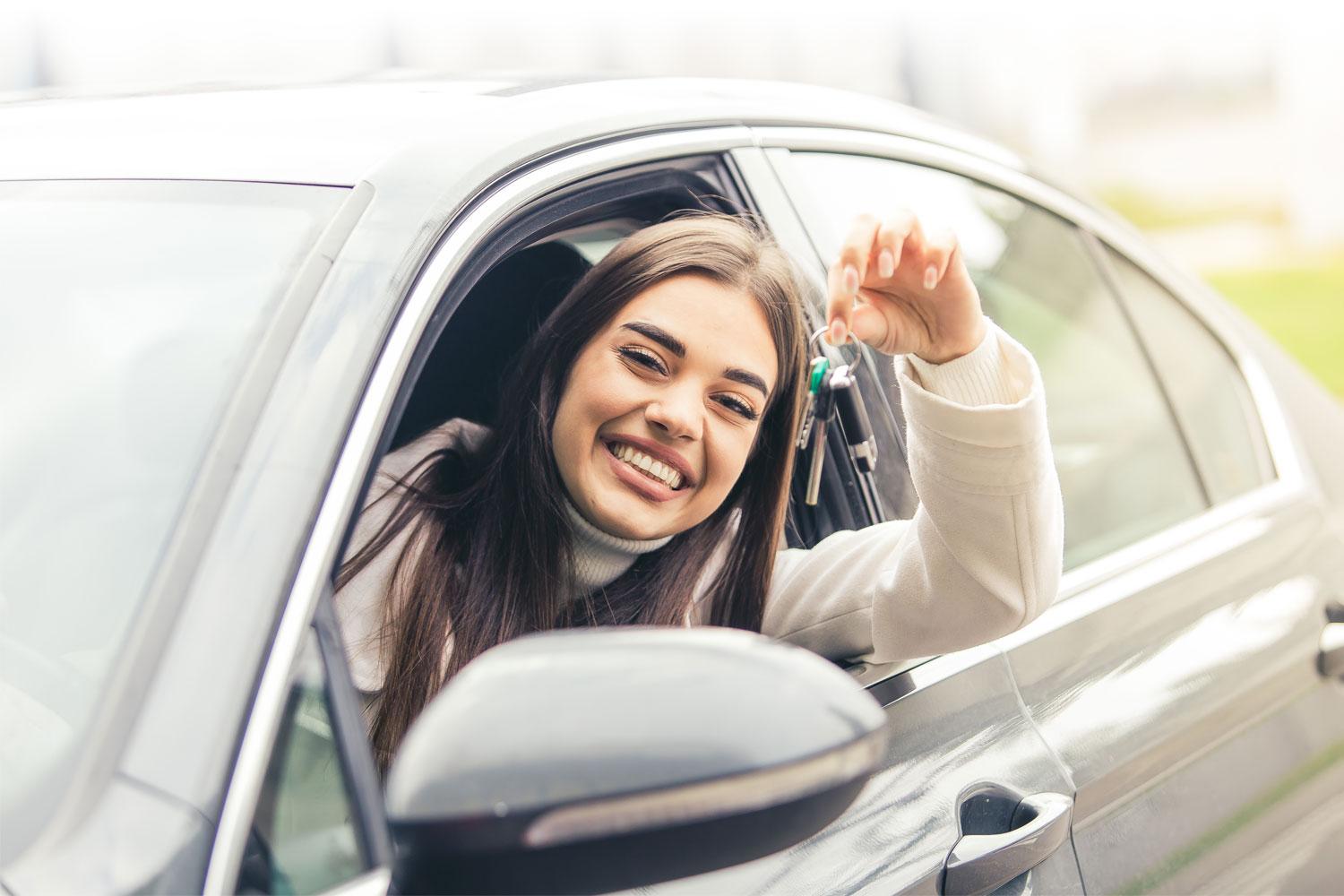 Woman sitting in the driver seat of a car, dangling car keys out the window