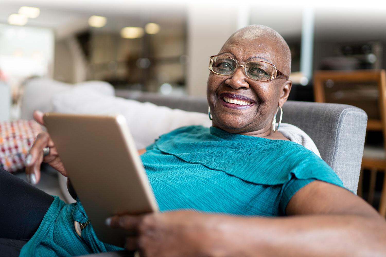 lady reading a tablet and smiling at the camera