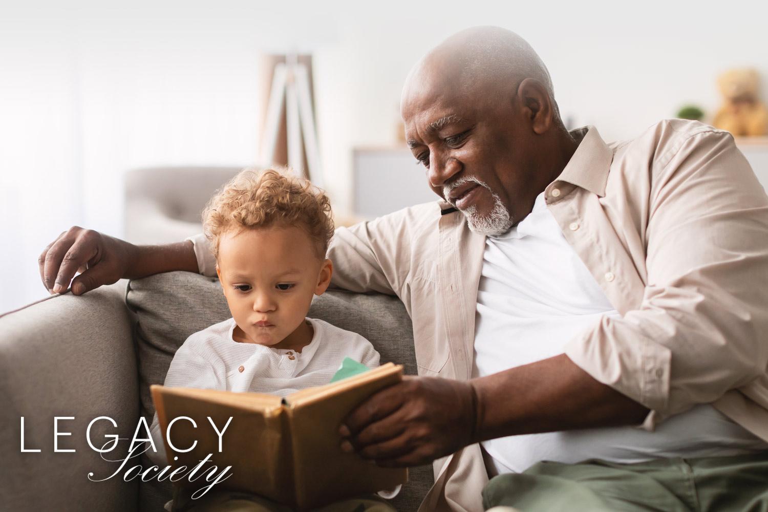 grandfather reading with his grandson on the couch, Legacy Society logo