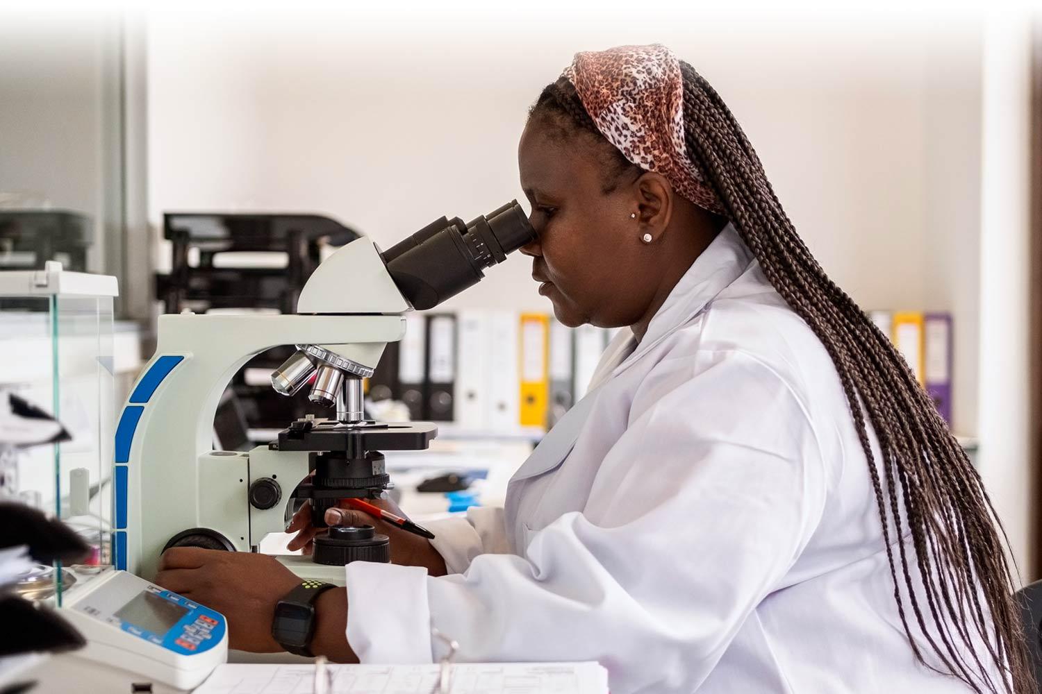 Two researchers in a lab, looking at a sample through a microscope.