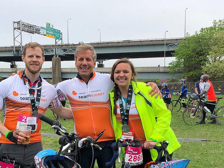 three cyclists taking a break while wearing Team Kidney uniforms