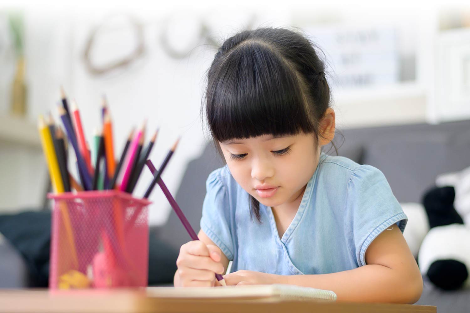young girl drawing with colored pencils